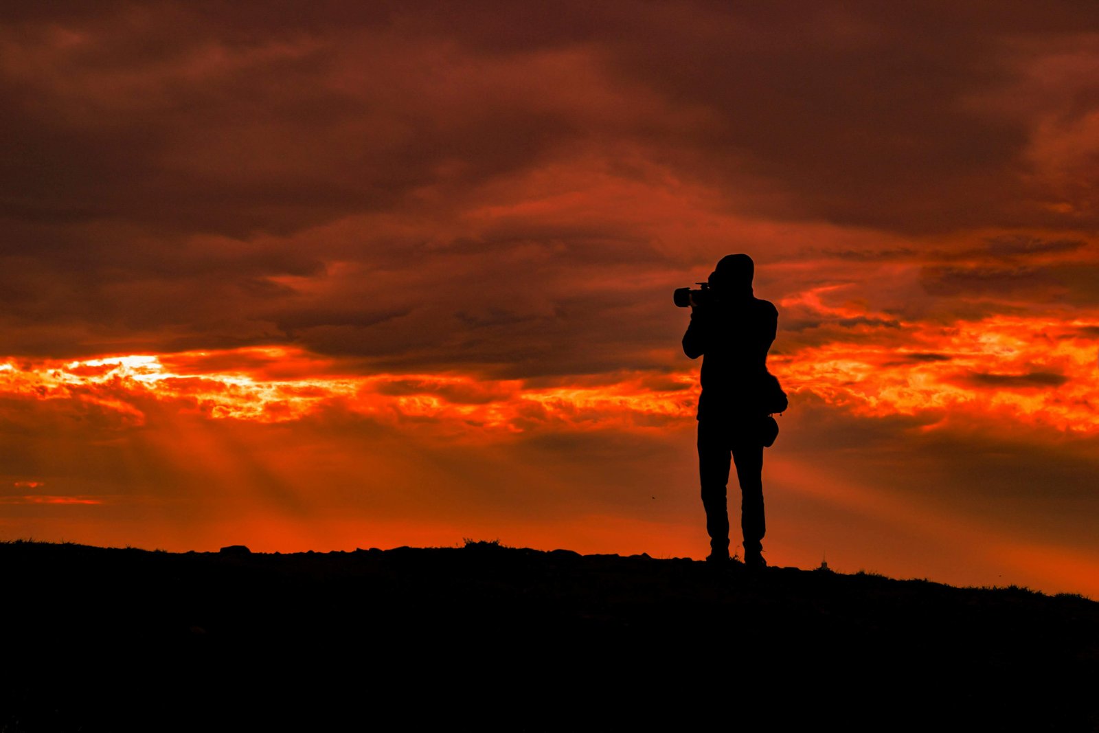 Photographer taking a photo on a hill at sunset